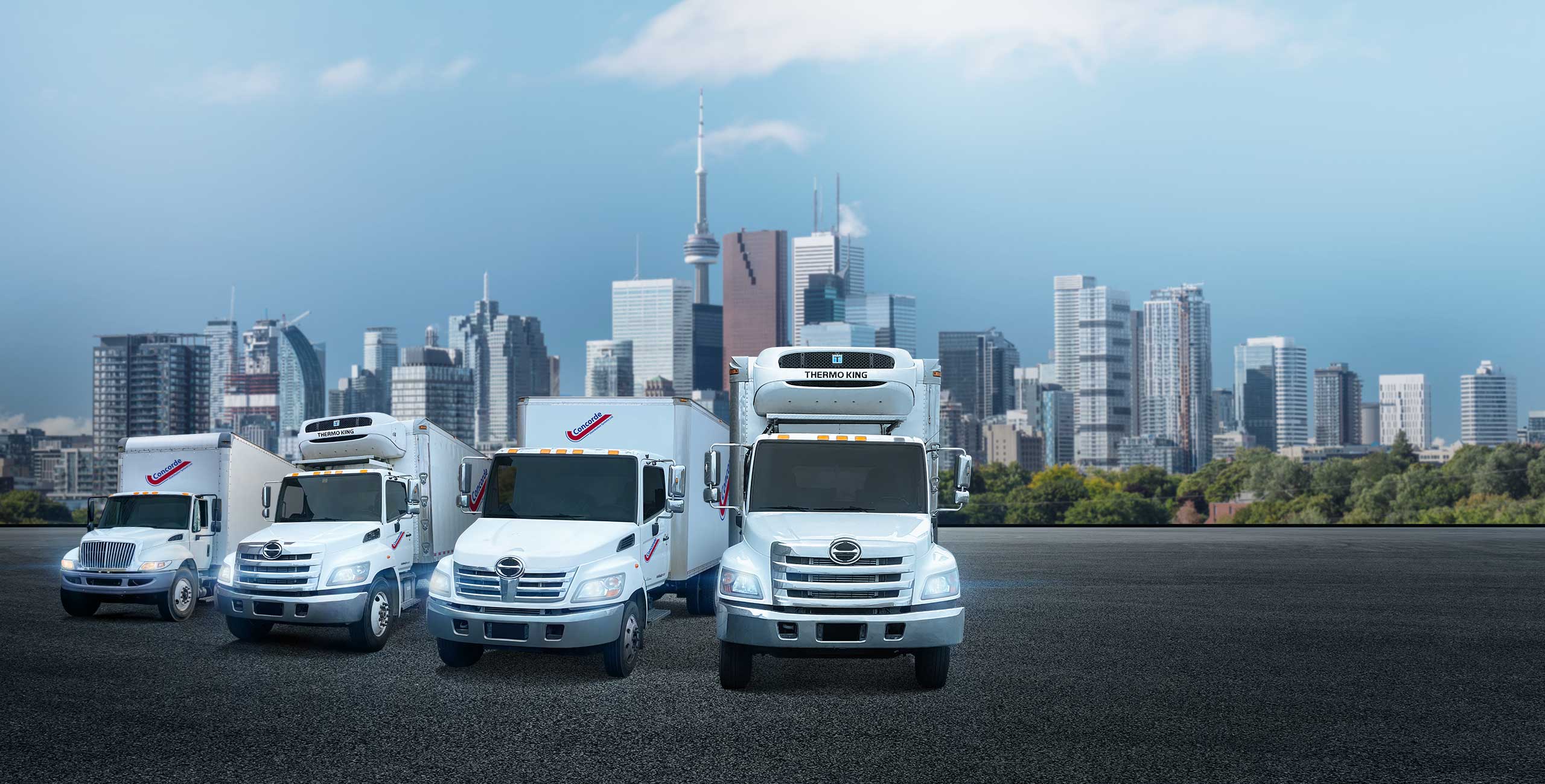 Concorde city truck, reefer, straight truck and second reefer in front of Toronto cityscape